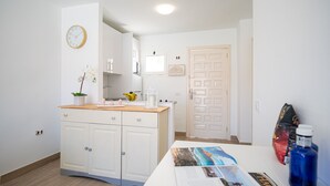 A modern kitchen with white cabinets, a wooden countertop, and a clock on the wall. - Modern Apartment with pool in El Castillo - Home For Guest (Antigua - Fuerteventura)