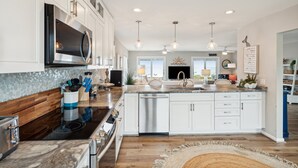 A modern kitchen with white cabinetry, stainless steel appliances, and a central island. - Oceanfront Luxury Home with Large Deck & Direct Beach Access - No Egrets (Folly Beach)