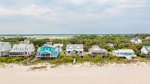 A beachfront property with multiple houses, some with elevated structures, and a sandy beach in the foreground. - Oceanfront Luxury Home with Large Deck & Direct Beach Access - No Egrets (Folly Beach)