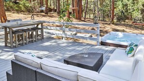 Une terrasse dotée de mobilier d’extérieur, d’un jacuzzi et d’une clôture en bois.