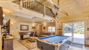Une pièce spacieuse équipée d’une table de billard, d’un canapé et d’une cheminée.