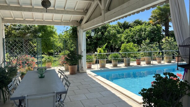 A covered patio area with a pool, outdoor seating, and potted plants. - Maison Individuelle, Preau Vers Piscine Privée Avec Plancha (Saint-Georges-du-Bois)