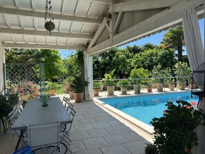 A covered patio area with a pool, outdoor seating, and potted plants. - Maison Individuelle, Preau Vers Piscine Privée Avec Plancha (Saint-Georges-du-Bois)