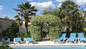 A swimming pool with blue water, surrounded by palm trees and a clear sky. - Maison Individuelle, Preau Vers Piscine Privée Avec Plancha (Saint-Georges-du-Bois)