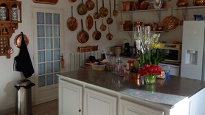 A kitchen with a central island, white cabinetry, copper cookware hanging on the wall, and a window with frosted glass. - Maison Individuelle, Preau Vers Piscine Privée Avec Plancha (Saint-Georges-du-Bois)