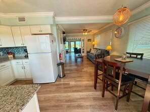 A kitchen with a refrigerator, stove, and microwave. There is a dining table with chairs and a window with blinds. - 2BR Beachfront Townhouse w/ private beach access (Cocoa Beach)