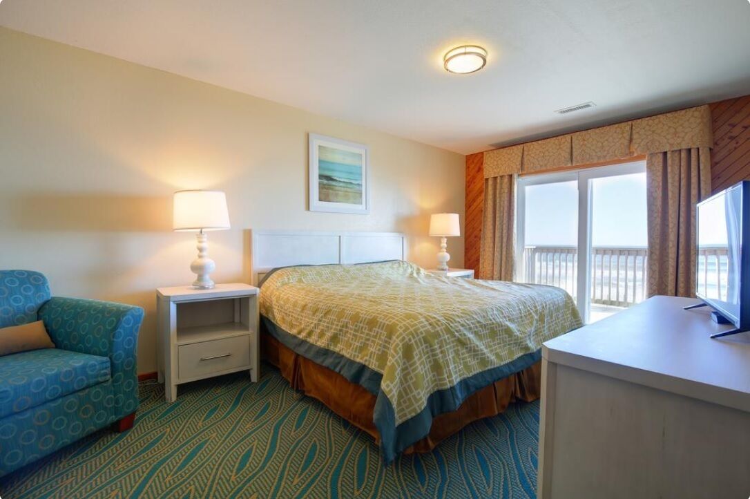 A hotel room with a bed, a desk, a chair, and a window with curtains.