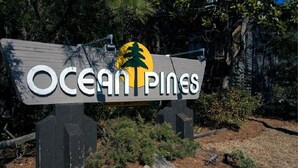 A sign with the text "Ocean Pines" and a palm tree logo. - Ocean Pines - 2BR/2BA Condo in Duck, NC (Duck)