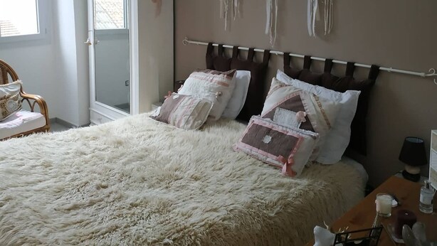 A bedroom with a large bed, a wardrobe, and wall decor. - Location Montagne (Veynes)