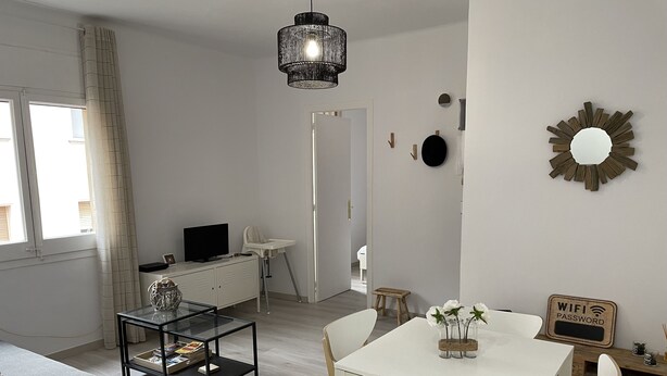 A modern living room with a TV, seating area, and dining space.