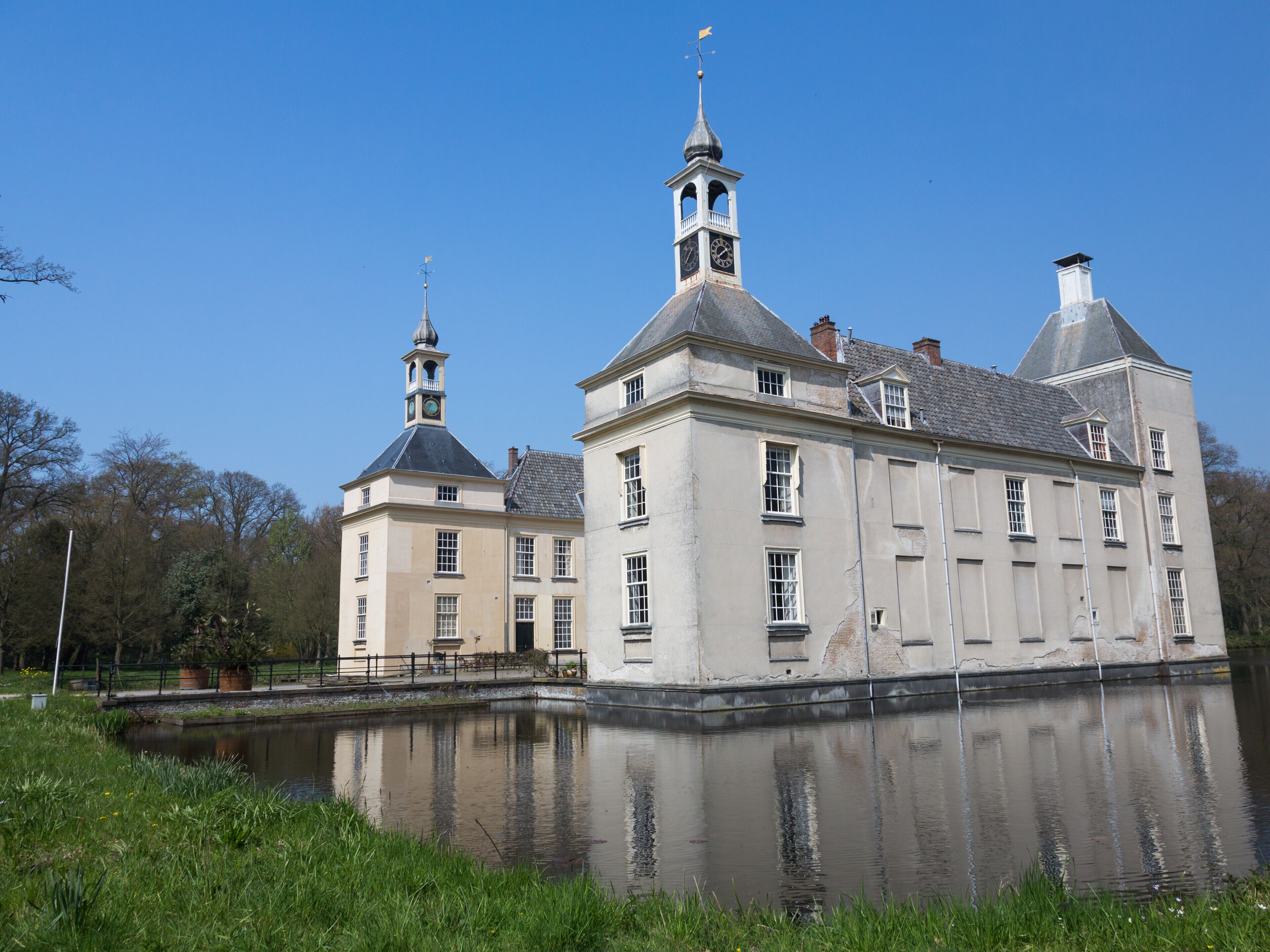 A historic building with a prominent tower and a large clock, situated by a calm water body.