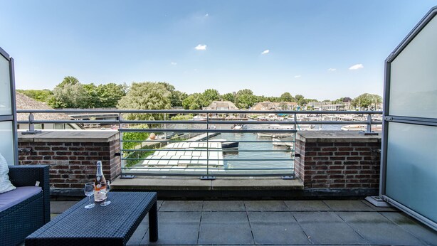 A balcony with a table, two chairs, and a bottle of champagne.
