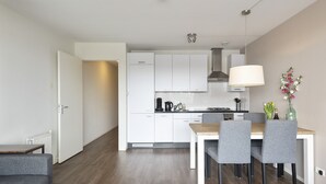 A modern kitchen with white cabinets, a dining table with chairs, and a pendant light.