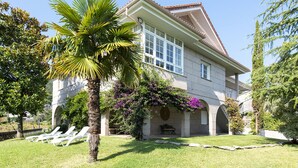 A two-story house with a balcony, a lawn, and a palm tree. - Villa Campo das Medas, in the middle of nature, with private salt pool (Donas Gondomar)