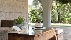 An outdoor seating area with a table, books, a hat, and potted plants. - Villa Campo das Medas, in the middle of nature, with private salt pool (Donas Gondomar)