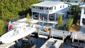 Une propriété située au bord de l’eau, dotée d’un quai, d’une piscine et d’une maison avec un balcon donnant sur l’eau.