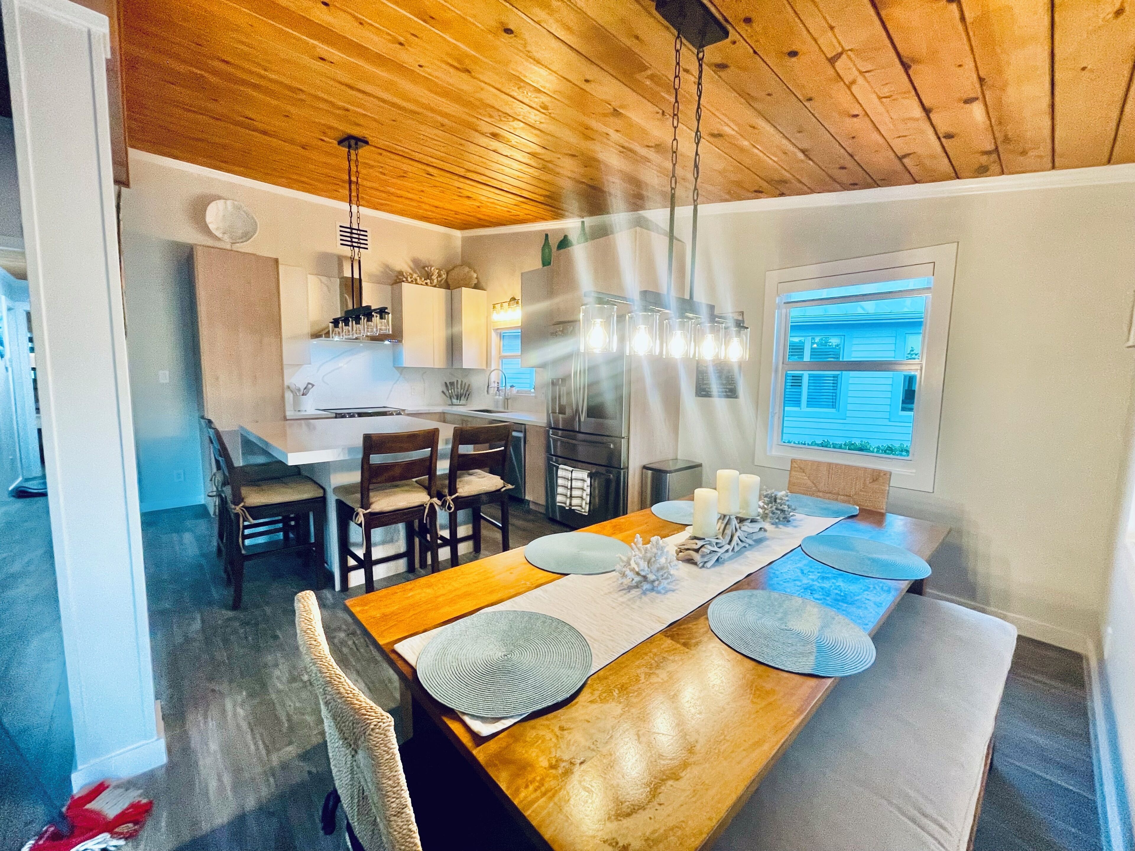A modern kitchen with wooden cabinets, a central island, and pendant lighting.