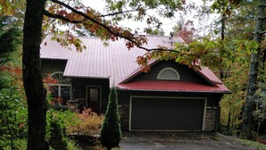 A house with a garage, surrounded by trees and a well-maintained lawn.