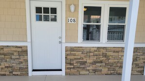 A building with a stone facade, a white door, and a window with a number plaque. - North Wildwood Beach Block 1 bdrm with Pool. (North Wildwood)