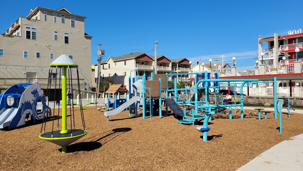 A playground with various play structures, surrounded by residential buildings. - North Wildwood Beach Block 1 bdrm with Pool. (North Wildwood)