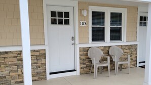 A building with a stone facade, a white door, and two wicker chairs outside. - North Wildwood Beach Block 1 bdrm with Pool. (North Wildwood)