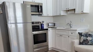 A compact kitchen with white cabinets, stainless steel appliances, and a wooden floor. - North Wildwood Beach Block 1 bdrm with Pool. (North Wildwood)