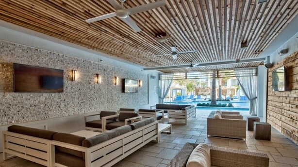 Un área de descanso moderna con pared de piedra, techo de madera y asientos cómodos.