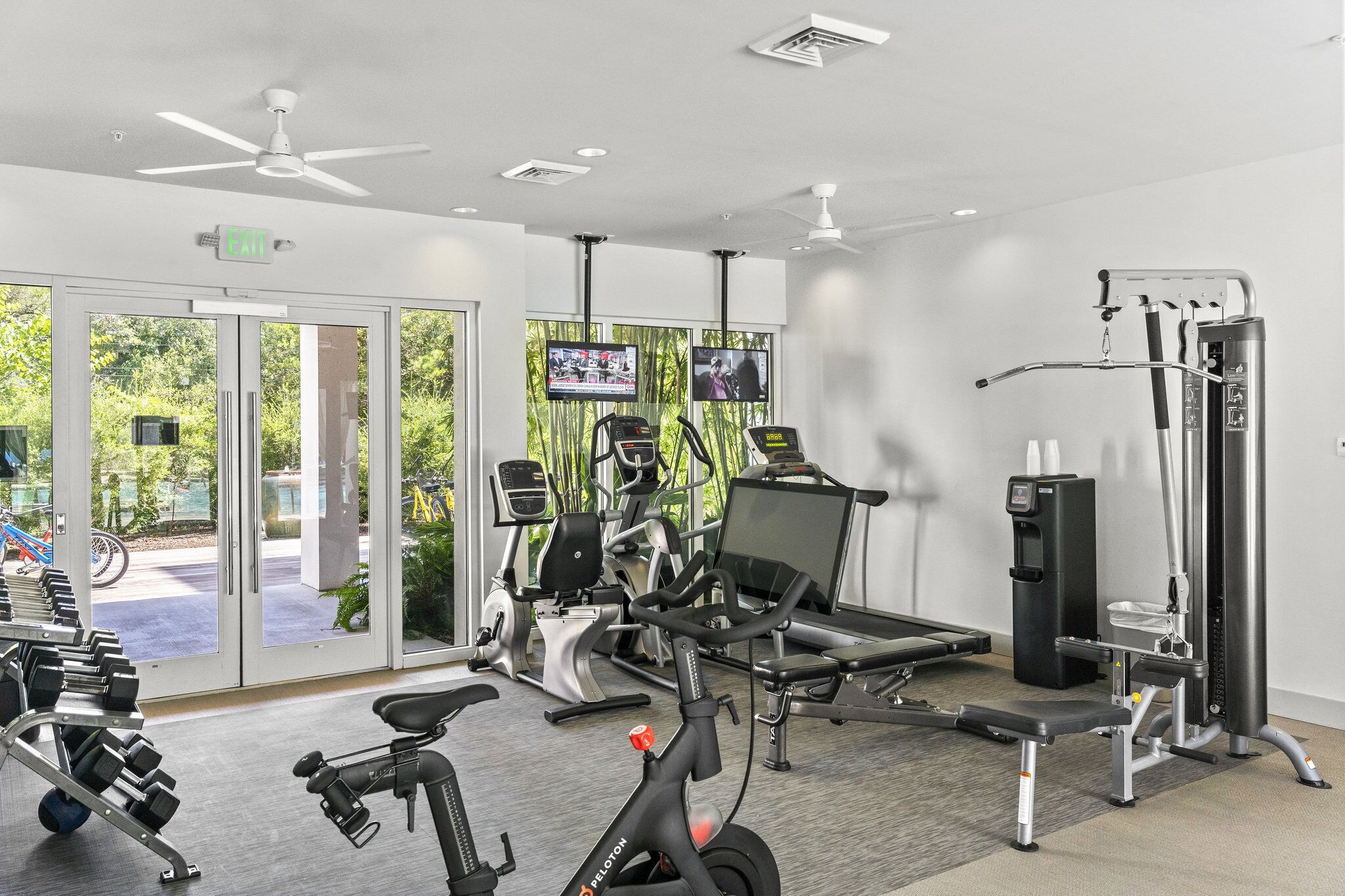 A gym with cardio equipment, weight machines, and dumbbells.