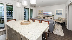 Una cocina moderna con encimera de granito, comedor con sofá y televisor.