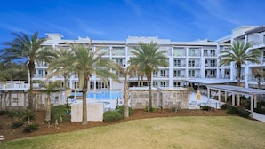 Un hotel con varios pisos, piscina y palmeras.