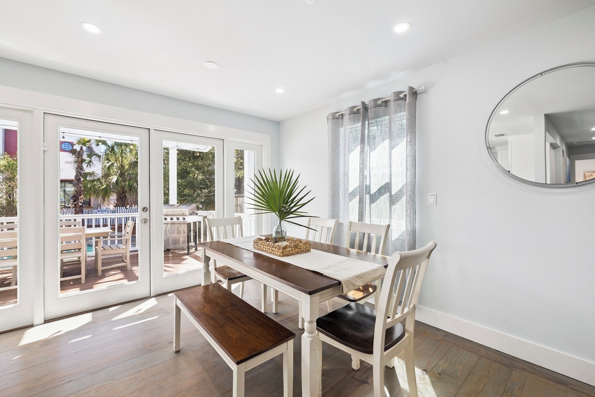 A dining area with a table, chairs, and a view of a pool and grill outside.