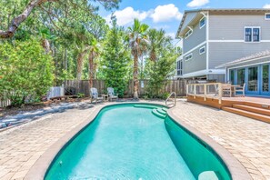 Relax by the pool surrounded by a patio and deck, with lounge chairs and a table nearby.