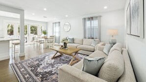 Ein geräumiges Wohnzimmer mit einer großen Couch, einem Couchtisch und einem Essbereich mit Tisch und Stühlen.