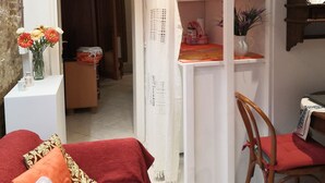 Una habitación acogedora con una cama, una silla, un estante con mantas dobladas y otra silla de madera.