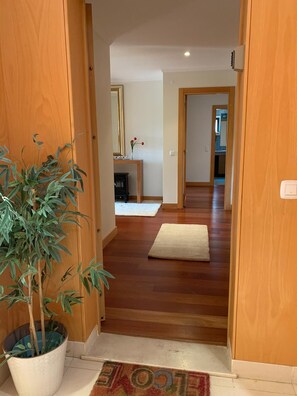 Enter a warm and inviting space with a cozy living area featuring a fireplace, wooden table, and a mirror.