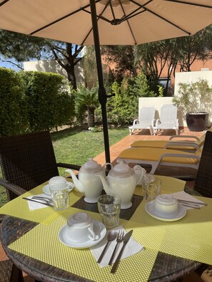 Enjoy a romantic meal under the shade of a large umbrella in our serene garden setting.