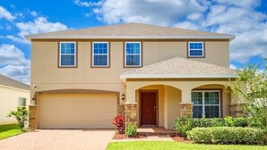 A two-story house with a garage, a front entrance with a door, and a small front yard with landscaping.