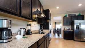 A modern kitchen with dark cabinetry, stainless steel appliances, and a granite countertop.