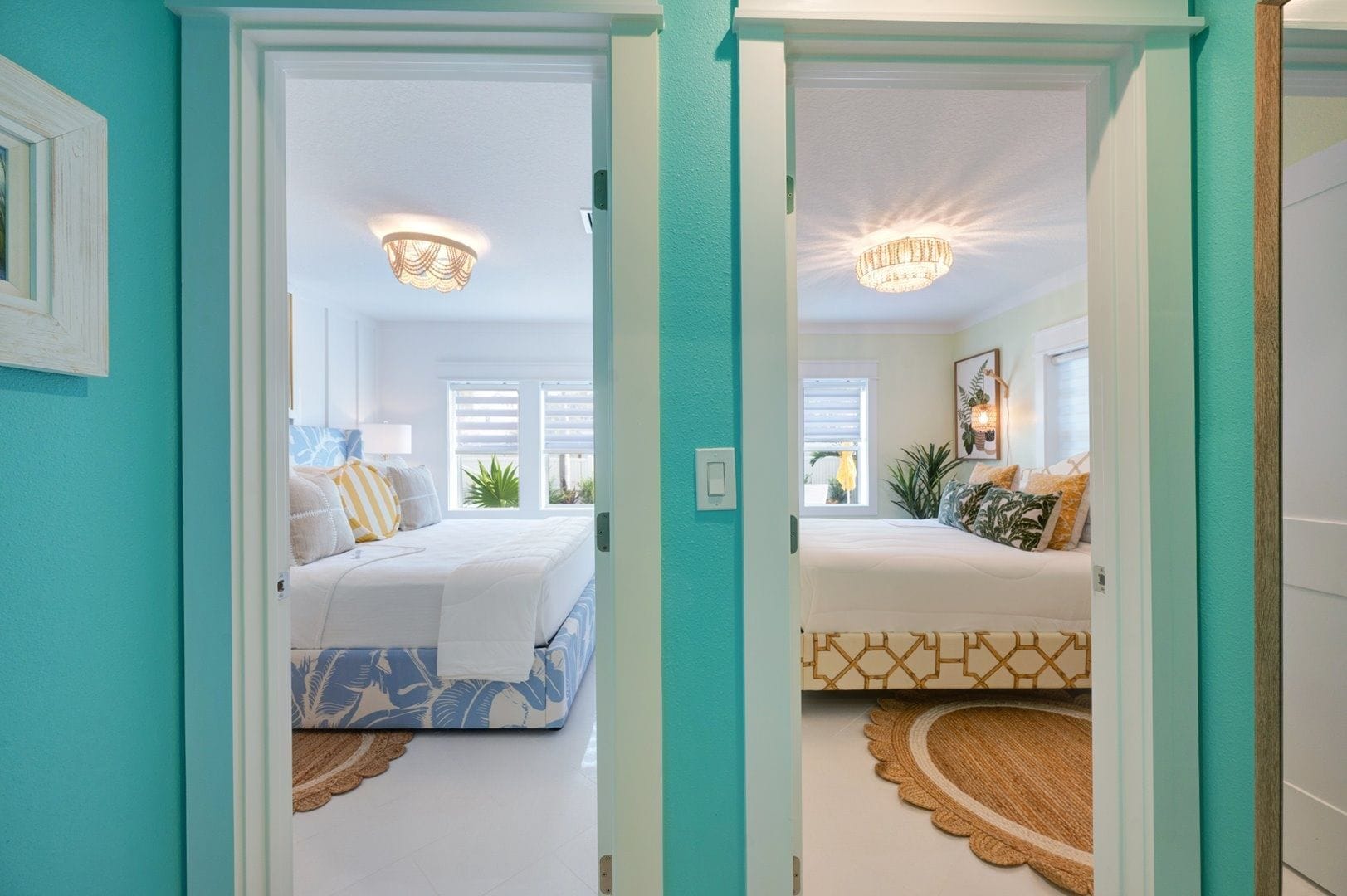 A hallway leading to two bedrooms with white walls, a ceiling fan, and a chandelier.