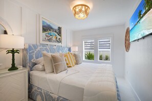 Une chambre à coucher avec un lit, une table de chevet, une lampe, un tableau et une fenêtre avec des volets.