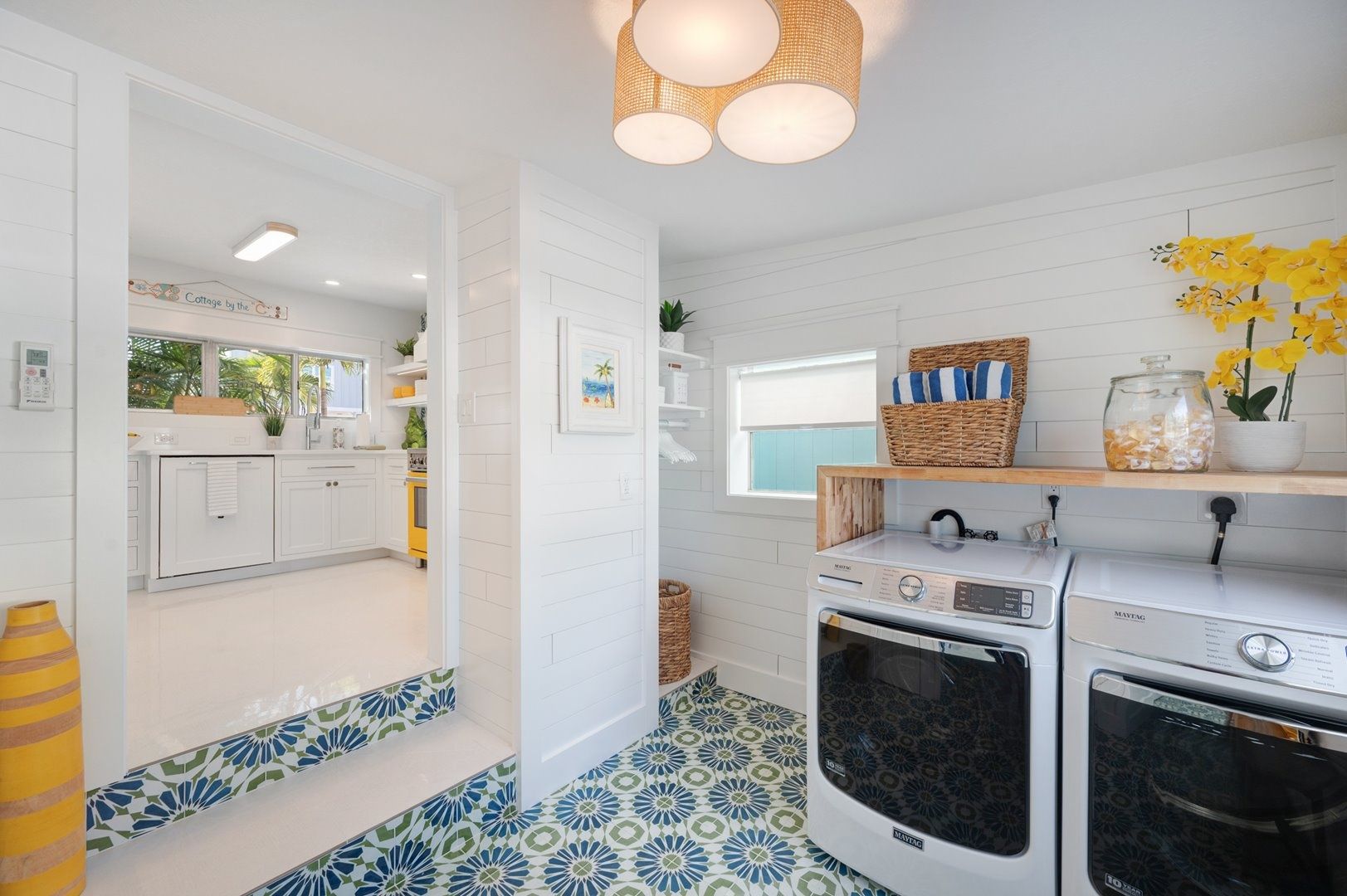 A modern kitchen with white cabinetry, a built-in oven, and a washing machine.
