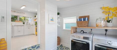 A modern kitchen with white cabinetry, a built-in oven, and a washing machine.