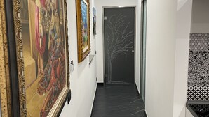 Un couloir doté d’un sol en marbre noir, de murs blancs et d’œuvres d’art encadrées.