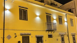 Un bâtiment jaune doté de nombreuses fenêtres, d’un balcon et de carreaux décoratifs.