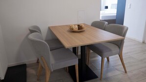 Un coin repas avec une table en bois, quatre chaises grises à revêtement rembourré et un panier de pain posé sur la table.