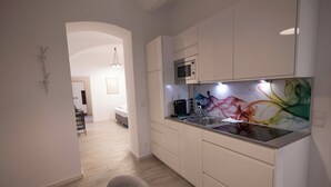 Une cuisine moderne avec des meubles blancs, un four à micro-ondes et un revêtement mural coloré.