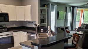 A modern kitchen with white cabinets, a built-in oven, and a central island with bar stools. - 3 Bedroom Condo in Myrtle Beach (Myrtle Beach)
