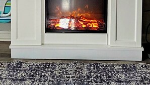 Valkoinen takka, jonka yläpuolella on televisio ja takan reunalla lamppu.