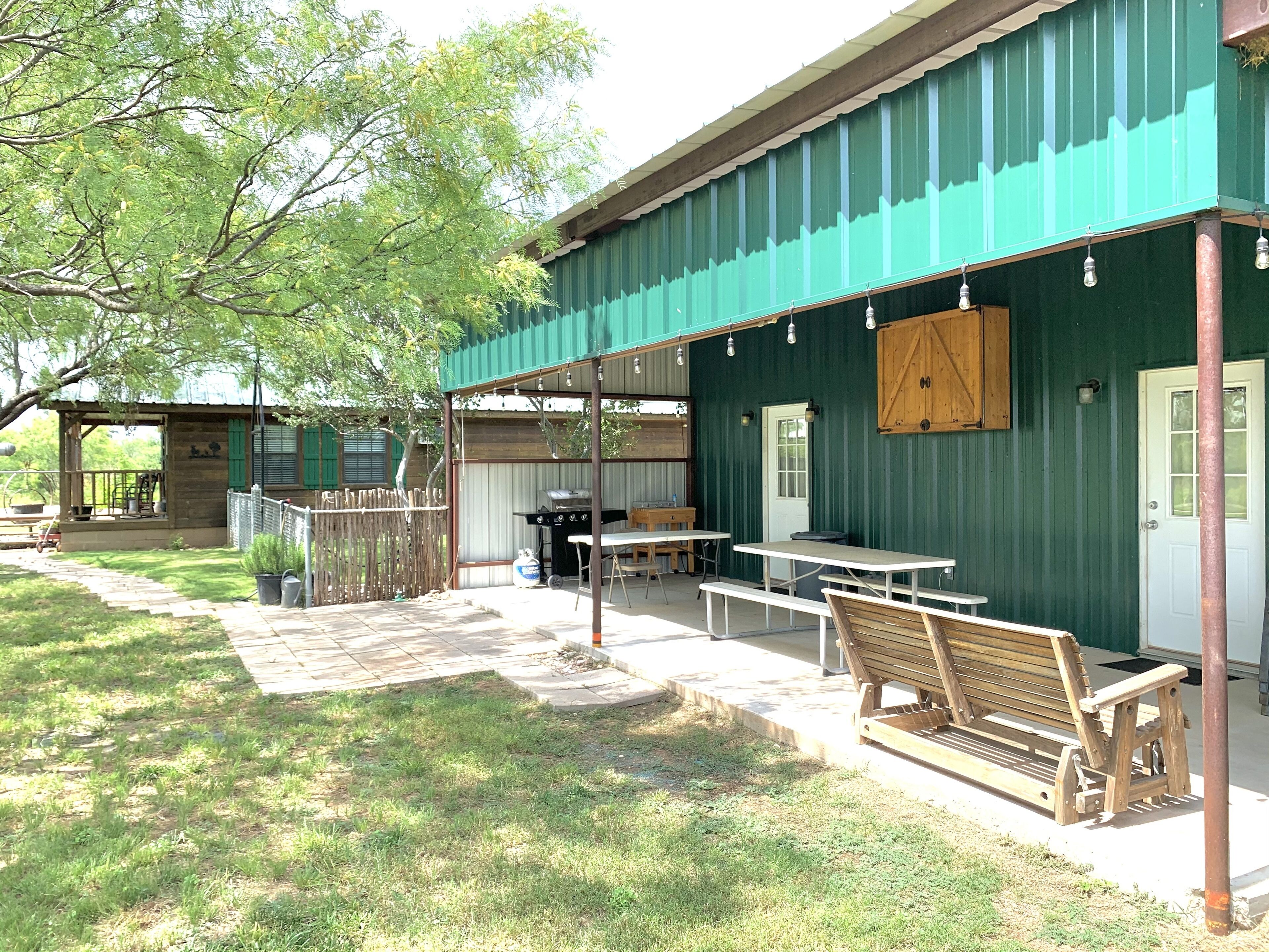 An outdoor patio area with a covered seating area, a barbecue grill, and a wooden fence.