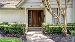 A house with the number 2051 on the front door, a small front porch, and a tree to the right.